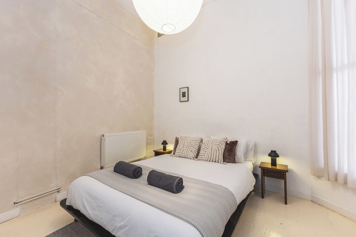 Ein Schlafzimmer mit einem Bett, zwei Nachttischen, einem Heizkörper und einem Bild an der Wand.