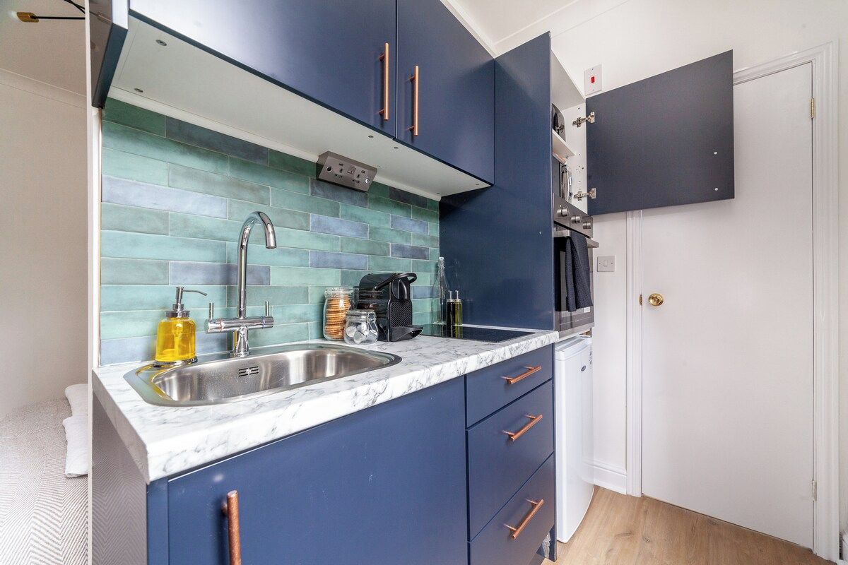 A compact kitchen with a sink, cabinets, and a microwave.