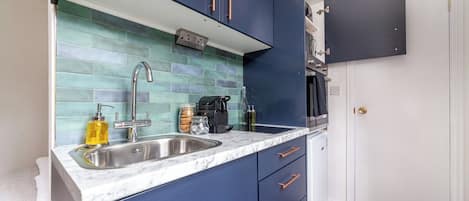 A compact kitchen with a sink, cabinets, and a microwave.