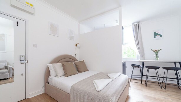 Quarto com cama, mesas de cabeceira, escrivaninha e uma cadeira.
