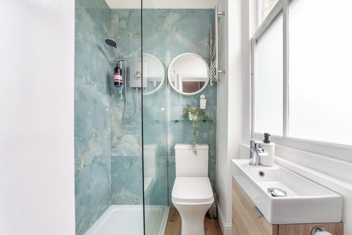 A modern bathroom with a glass-enclosed shower, a toilet, and a sink with a mirror.