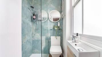 A modern bathroom with a glass-enclosed shower, a toilet, and a sink with a mirror.