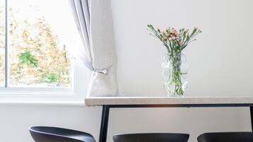 A kitchen with a window, a vase with flowers, and a framed picture on the wall.