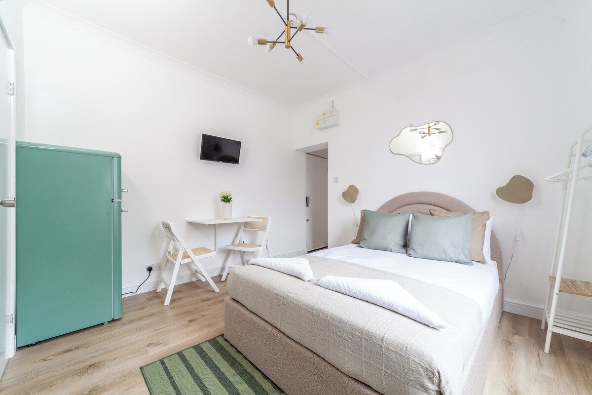 A bedroom with a bed, a desk, a television, and a wardrobe.