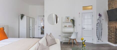A modern hotel room with a bed, a desk, and a seating area.