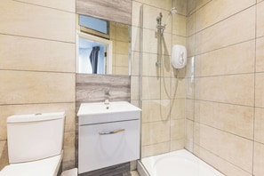A bathroom with a toilet, a sink, and a shower area. - Fabulous Studio Flat Kilburn - Central Location (Greater London)