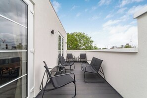 Ein Balkon mit Sitzgelegenheit, inklusive Stühle und Tisch.