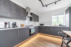 Eine moderne Küche mit grauen Schränken, einem eingebauten Backofen und einem Fenster für natürliches Licht.