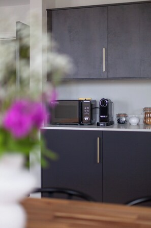 Eine Küche mit einer Mikrowelle, einer Kaffeemaschine und Gläsern auf der Arbeitsfläche.