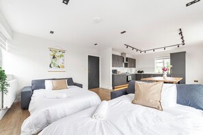 Ett modernt hotellrum med två sängar, ett litet pentry och utsikt över trädgården.