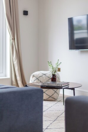 Ein modernes Wohnzimmer mit einer Couch, einem Hocker und einem Couchtisch mit einem Buch mit dem Titel 'ALL ABOUT VES'.