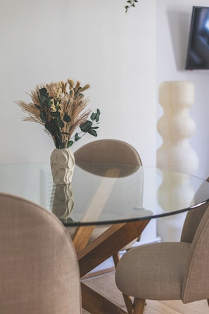 A modern dining area with a glass table, two chairs, and a vase with dried plants. - Tower Bridge 2 Bedroom Flat | Sleeps 5 | Great (Greater London)