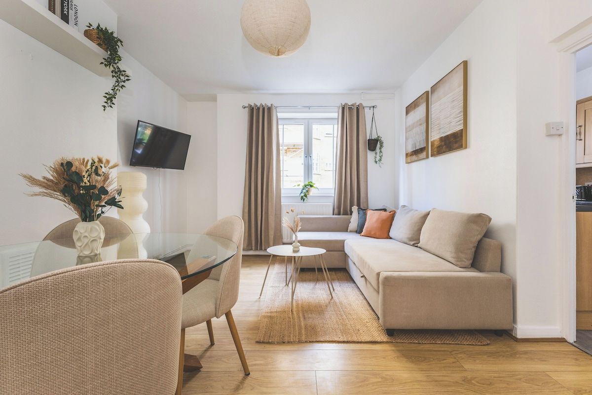 Un salon moderne avec un canapé, une table à manger en verre et un téléviseur fixé au mur.