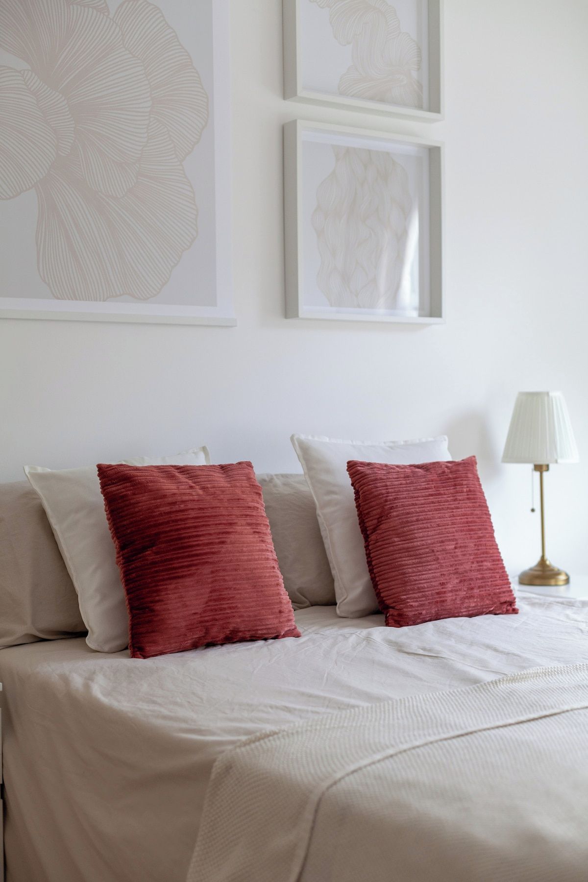 Een netjes opgemaakt bed met twee kussens, een bedlampje en een wanddecoratie in een lijst.