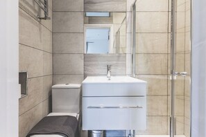 A modern bathroom with a glass shower enclosure, a white sink, and a toilet. - Stylish & Petit Studio flat Kilburn (Greater London)