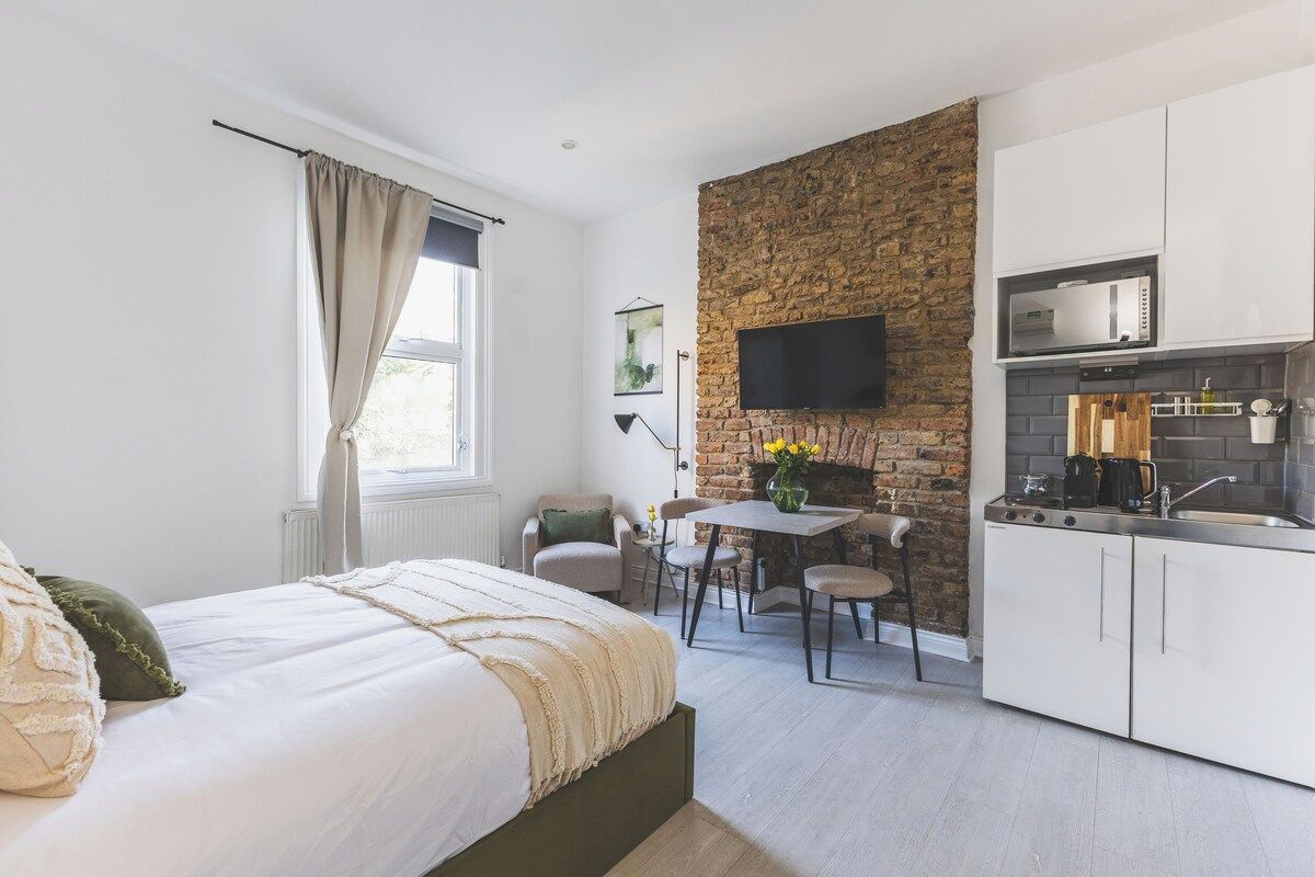 Une chambre compacte comprenant un lit, une petite table et une kitchenette équipée d’un four à micro-ondes.