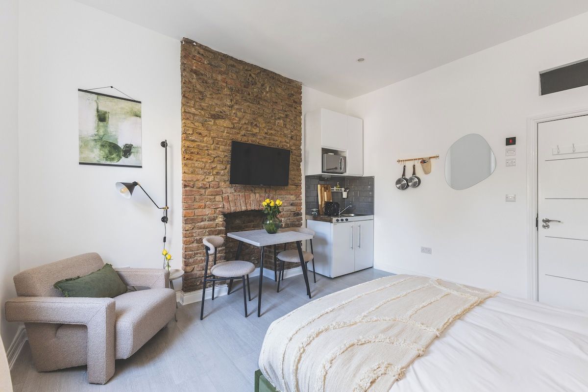 A compact living space with a kitchenette, a dining area, and a bed.