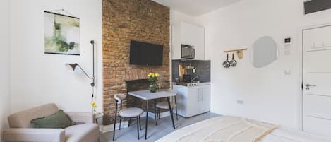 A compact living space with a kitchenette, a dining area, and a bed.