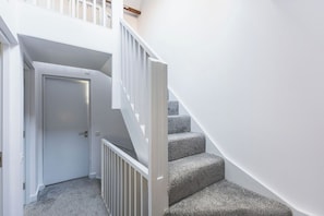 A staircase with white railings and carpeted steps leading to a door. - New Spacious 3 bed flat Duplex, Whitechapel (Greater London)