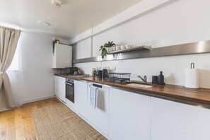 A modern kitchen with white cabinets, a wooden countertop, and a stainless steel range hood. - New Spacious 3 bed flat Duplex, Whitechapel (Greater London)