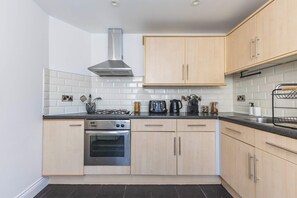 A modern kitchen with a gas stove, oven, and stainless steel range hood. - Beautiful Stratford House w/ Parking - Sleeps 8 (Greater London)