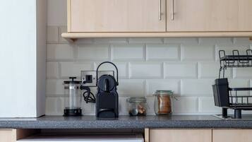 A kitchen with a washing machine, wooden cabinets, and a countertop with various items.