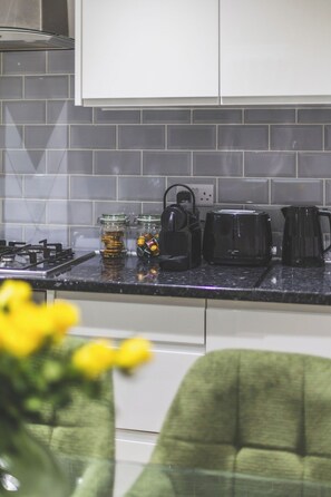 A kitchen with a gas stove, a coffee maker, and a jar of snacks. - Gorgeous 3 bed flat, Kilburn - Central Location (Greater London)