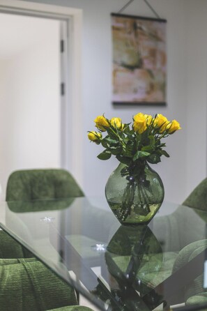 Ein Glastisch mit einer Vase voller gelber Blumen.