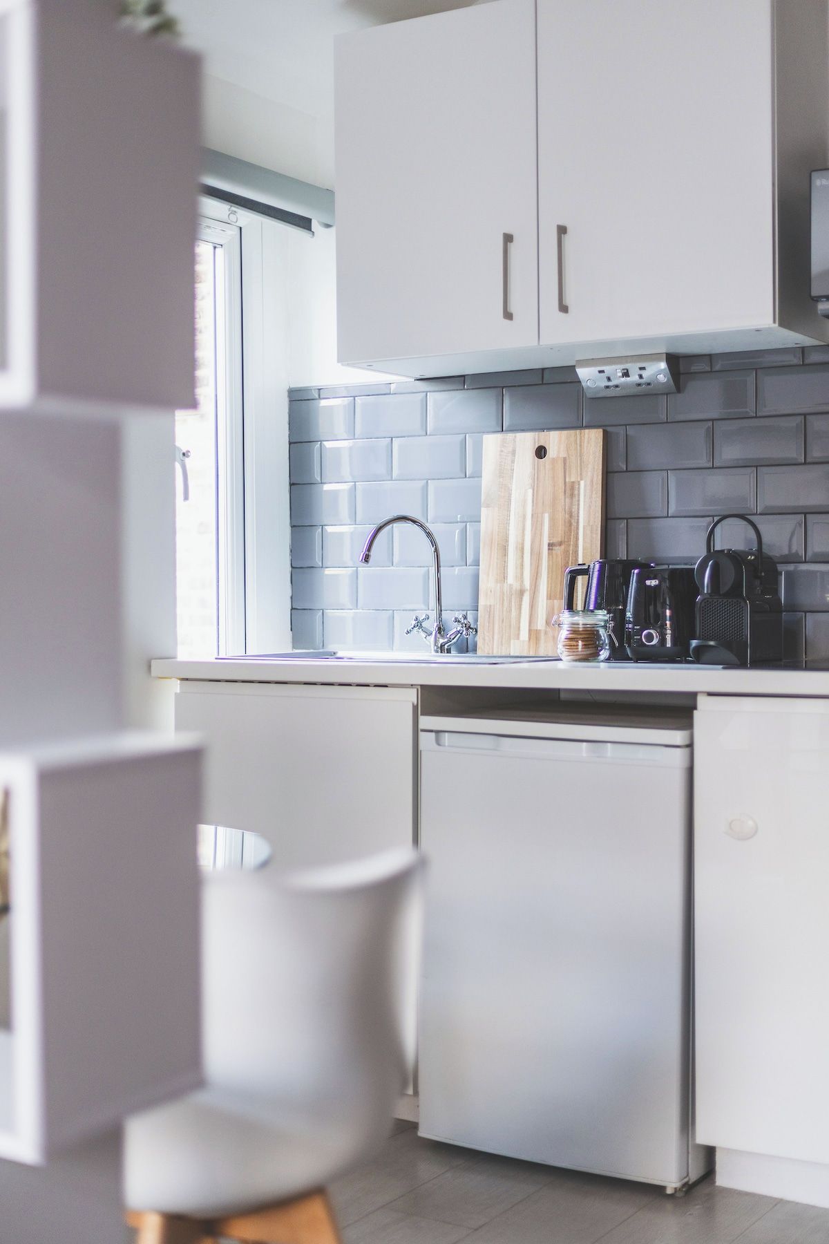 Una cucina moderna con mobili bianchi, una schiena grezza e una lavastoviglie.