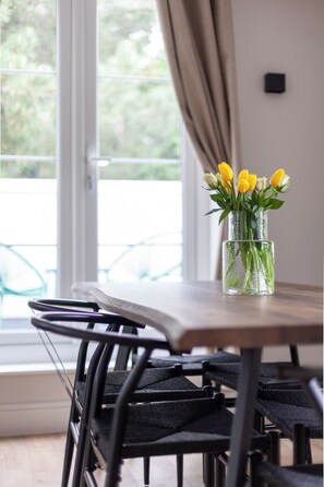 A dining table with chairs, a vase with flowers, and a window with curtains. - Chic and Classy 2BR Penthouse w/ Parking, 6 Guests (Greater London)