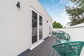A building exterior with large windows, a white wall, and a deck area with green chairs. - Chic and Classy 2BR Penthouse w/ Parking, 6 Guests (Greater London)
