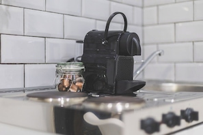 A kitchen with a stove, a black appliance on top, and a jar with nuts. - Stunning studio flat, Kilburn/West Hampstead (Greater London)