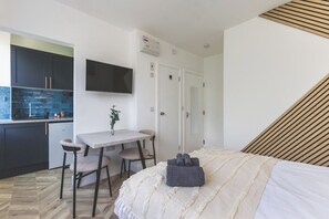 Une chambre moderne équipée d’un lit, d’un bureau et d’une kitchenette.