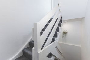 Eine Treppe mit weißen Geländern und grauen Teppichstufen.