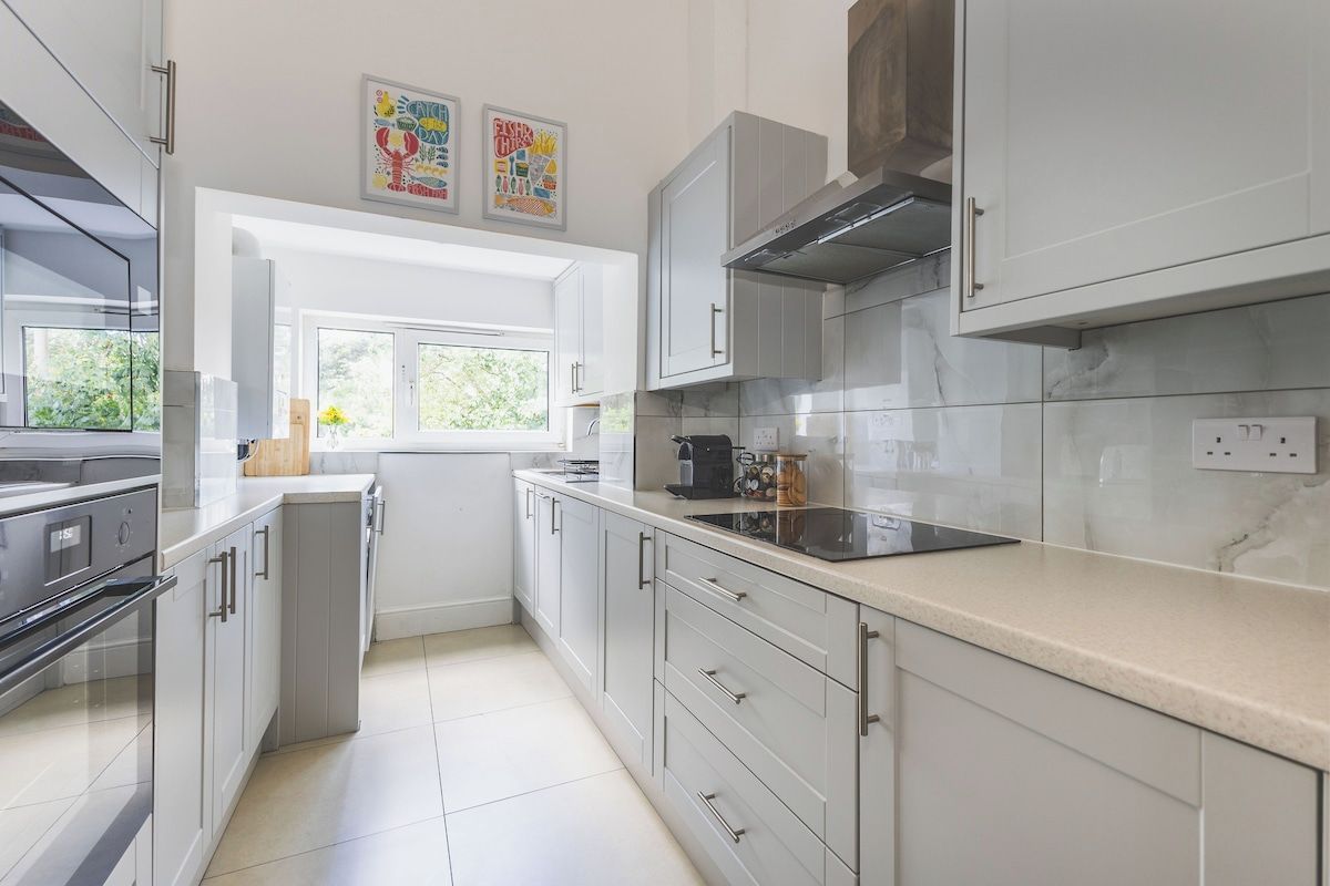 A modern kitchen with white cabinets, a built-in oven, and a window providing natural light.