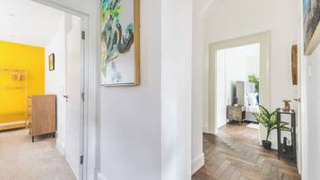 A hallway with a wooden floor, a white door, and a yellow wall.