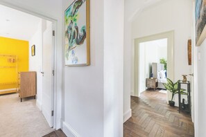 A hallway with a wooden floor, a white door, and a yellow wall. - 3 bed | Sleeps 7 | Private Parking |Great Location (Greater London)