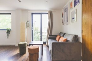 Ein modernes Wohnzimmer mit einer Couch, einem Hocker und einem Tisch.