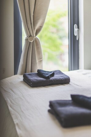 A neatly made bed with folded towels and a window with curtains. - Spacious 3Bed 3Bath Hackney Downs, 3min to Station (London)
