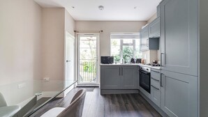 A modern kitchen with grey cabinets, a microwave, and a stove. - Lovely 2BR Flat, 15Minutes to Wembley, Sleeps 5ppl (Greater London)