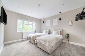 Ein Schlafzimmer mit zwei Betten, einem großen Fenster und einer Heizung.