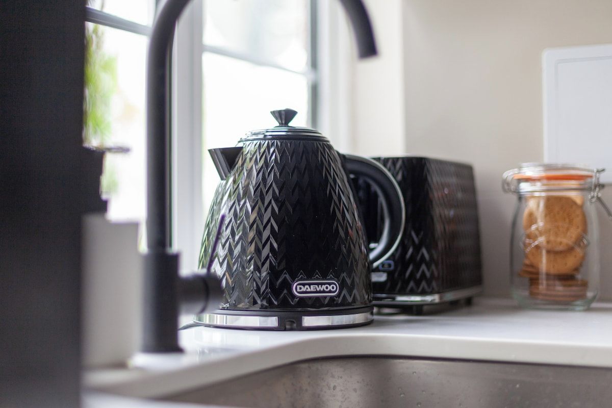 A kitchen counter with a Daewoo coffee maker, a toaster, and a glass jar with cookies.