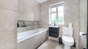 A modern bathroom with a bathtub, toilet, and sink. - Lovely 2BR Flat, 15Minutes to Wembley, Sleeps 5ppl (Greater London)