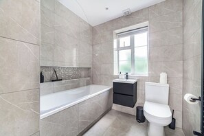 Ein modernes Badezimmer mit Badewanne, Toilette und Waschbecken.