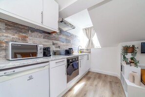 Eine moderne Küche mit weißen Schränken, einer eingebauten Mikrowelle, einem Geschirrspüler und einem Fenster mit Vorhängen.