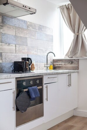 Una cocina moderna con horno empotrado, cafetera y lavabo.