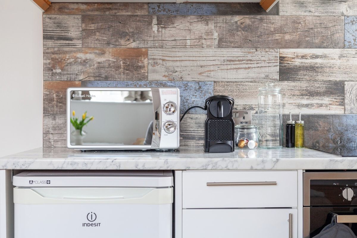 Una cucina con un forno a microonde bianco, una macchina da caffè e una lavastoviglie.