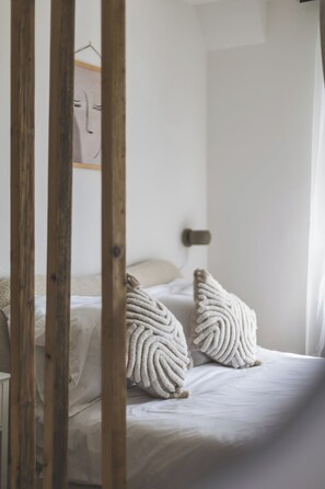 A bedroom with a bed, two textured pillows, a wooden headboard, and a white wall. - Stunning Studio Flat Highbury - GREAT Location (Greater London)
