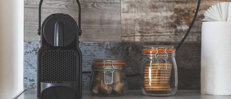 A kitchen counter with a coffee maker, two glass jars with metal lids, and a white paper towel holder.