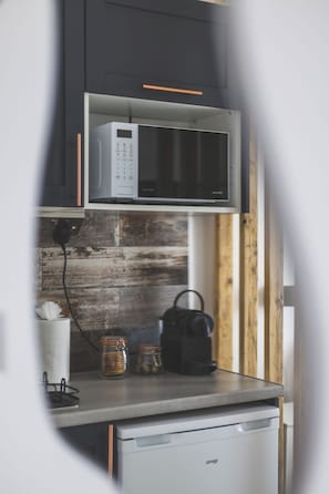 A compact kitchen with a microwave, a kettle, and storage jars on the counter. - Stunning Studio Flat Highbury - GREAT Location (Greater London)